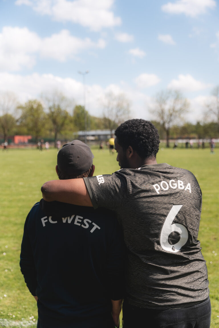 Zwei Spieler stehen Arm in Arm am Spielfeldrand.